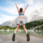 woman jumping wearing blue sports bra and grey shorts