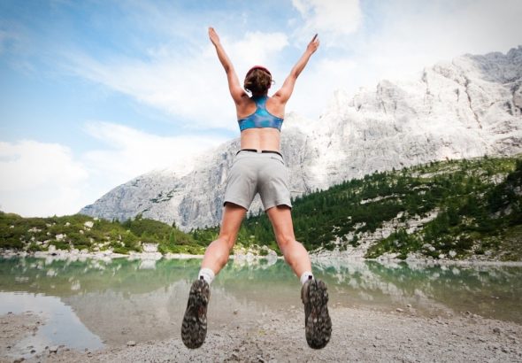 woman jumping wearing blue sports bra and grey shorts